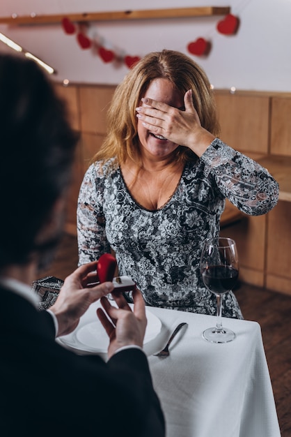 Um homem de meia idade faz uma proposta de casamento para uma mulher no jantar