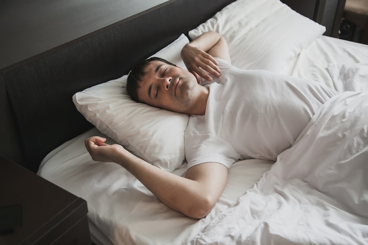 Foto um homem de meia-idade na cama em seu quarto acorda de manhã com um sorriso no rosto. o conceito de sono saudável.