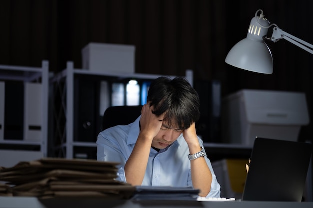 Um homem de negócios a fazer horas extras no escritório. Ele sentia-se cansado.