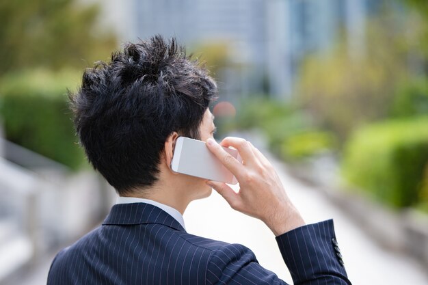 Um homem de negócios asiático usando um smartphone na rua