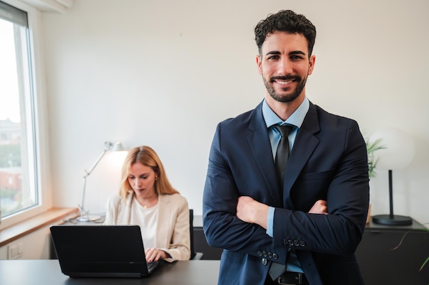 Foto um homem de negócios de braços cruzados sorrindo e olhando para a câmera em pé no escritório corporativo escritório homem