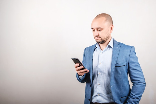 Um homem de negócios em uma jaqueta Olha para o telefone. O conceito de trabalho remoto