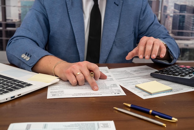 Um homem de negócios em uma jaqueta preenche formulários fiscais e faz cálculos na mesa
