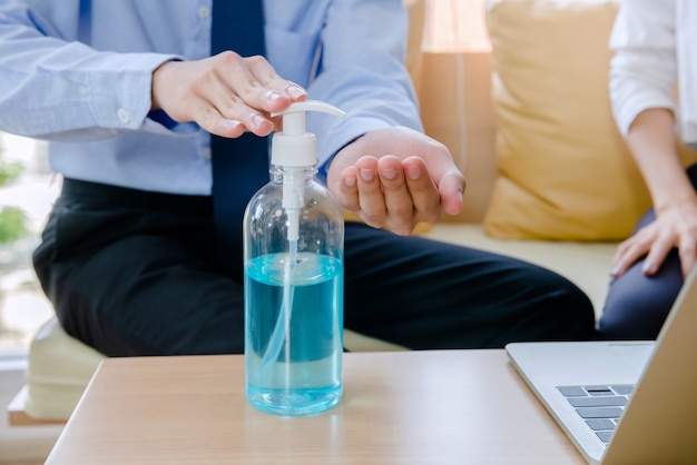 Um homem de negócios está usando um gel desinfetante para lavar as mãos