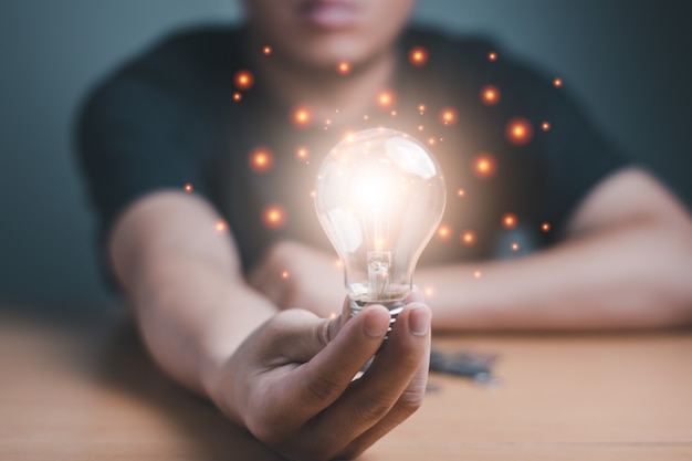 Um homem de negócios segurando a lâmpada de luz sucesso de salvar e manter o conceito, ideia de luz gráfica de computador