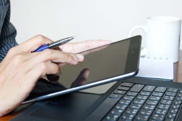 Foto um homem de negócios, trabalhando na tablet e laptop.