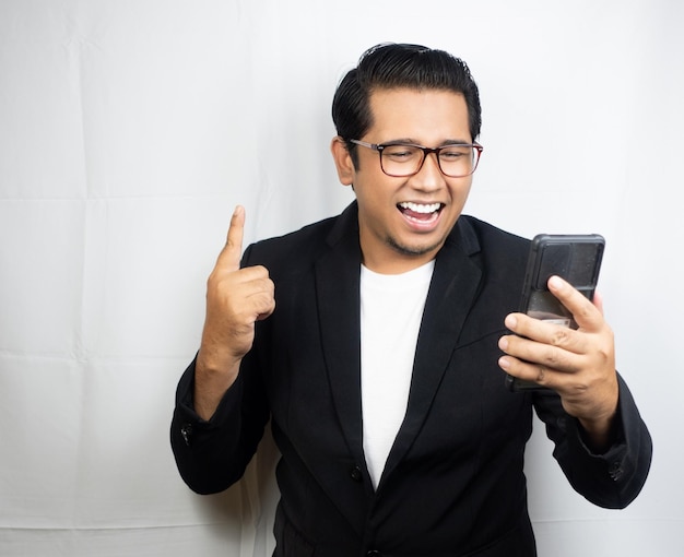 um homem de óculos e jaqueta preta está apontando para um telefone.