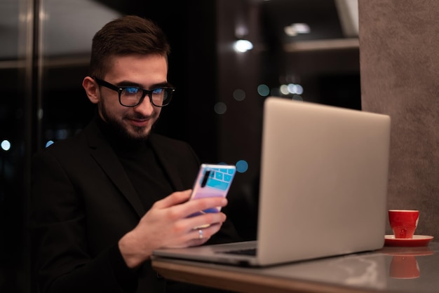 Um homem de óculos está olhando para seu telefone com a hora de 11:00.