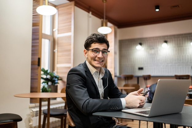 Um homem de óculos trabalha em um escritório usa um laptop faz um relatório on-line sobre o projeto