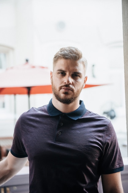 Um homem de pólo roxo e posando para anunciar roupas masculinas. Tiro para loja de roupas masculinas