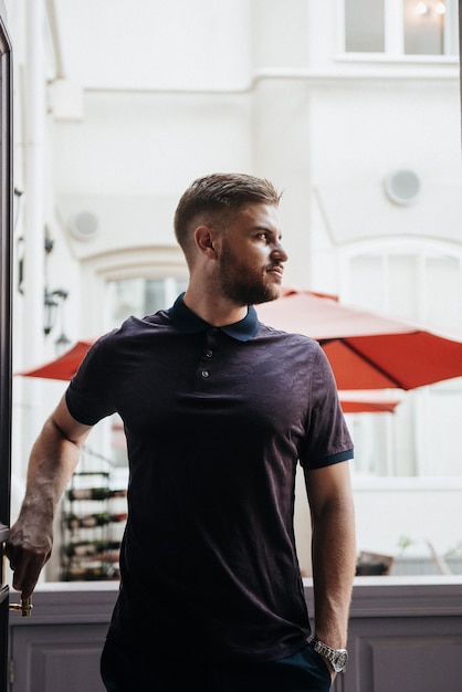 Um homem de pólo roxo e posando para anunciar roupas masculinas. Tiro para loja de roupas masculinas