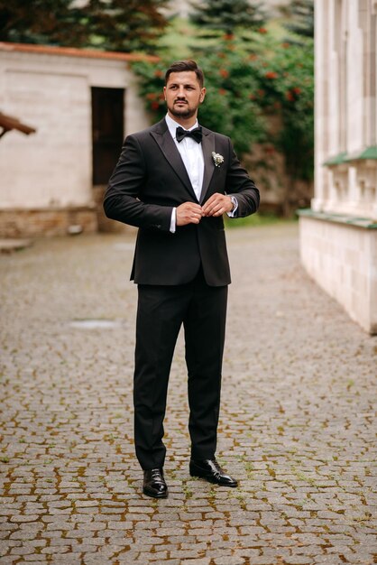 Foto um homem de smoking está em uma rua de paralelepípedos