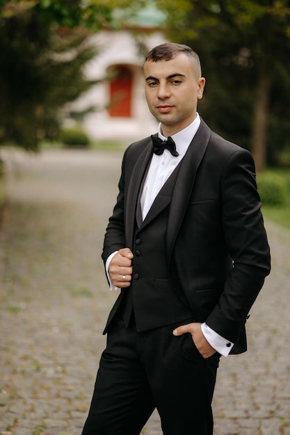 Foto um homem de smoking está num parque.