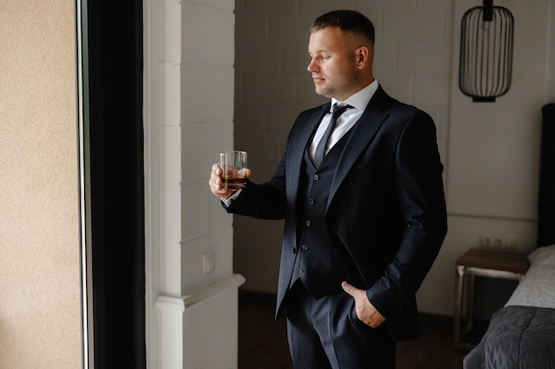 Um homem de smoking segura um copo de vinho.