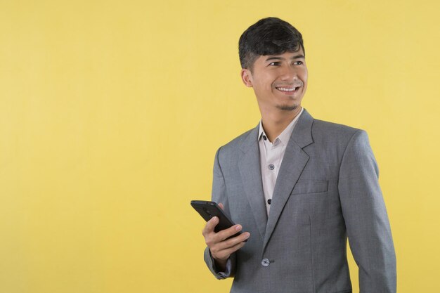 Um homem de terno cinza segura um telefone na mão.