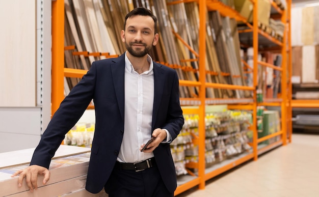 Um homem de terno de negócios ao lado de uma vitrine de materiais de construção em um hipermercado