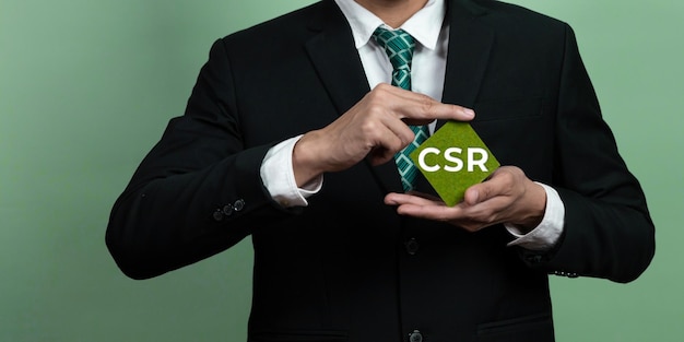 Um homem de terno segura um cubo verde com CSR nele.