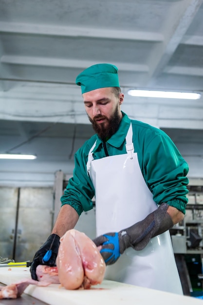 Um homem de uniforme verde e avental branco segura um pedaço de carne.