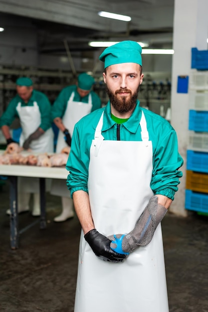 Foto um homem de uniforme verde está na frente de um frango cru.