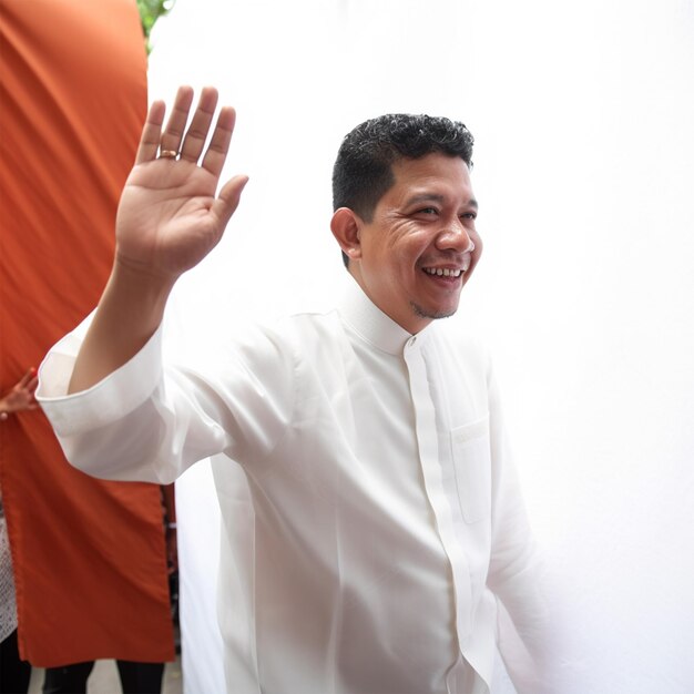 Foto um homem de vestido branco acenando para a câmera