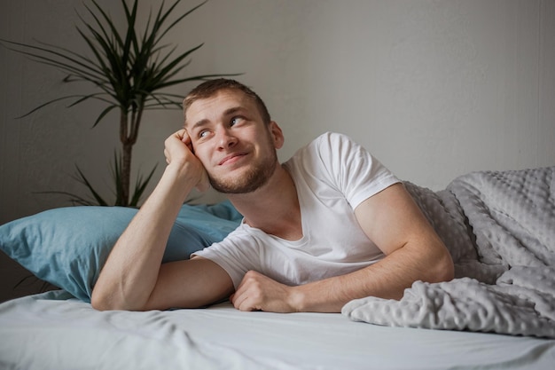 Um homem deita na cama e olha pela janela