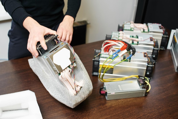 Um homem desempacota uma caixa de equipamento para minerar bitcoin criptomoeda