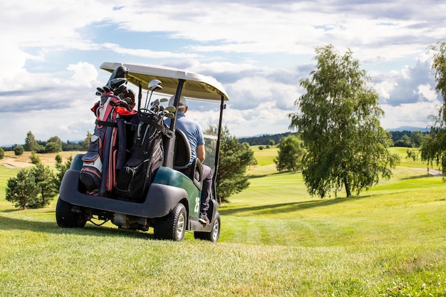 Um homem dirigindo um carrinho de golfe em um campo de golfe