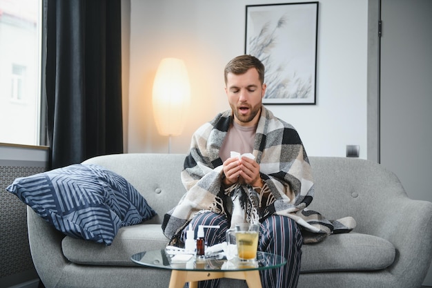 Um homem doente senta-se em casa em um sofá cinza com um cobertor Proteção contra doenças coronavírus doença gripe