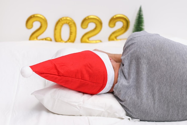 Um homem dorme com um chapéu de natal no contexto do número escrito com balões.