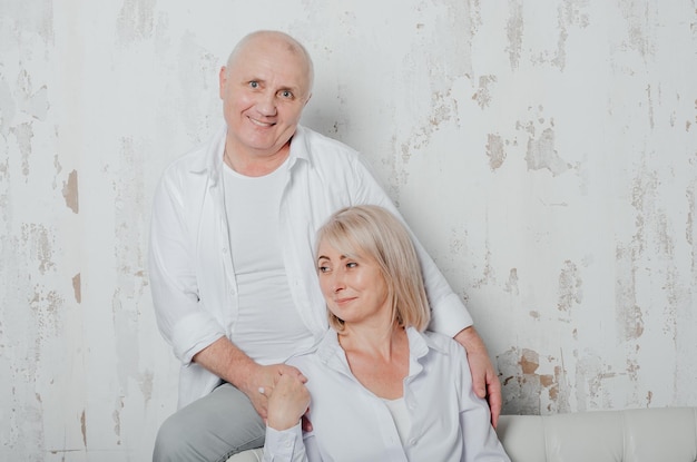 um homem e sua esposa em camisas brancas no sofá