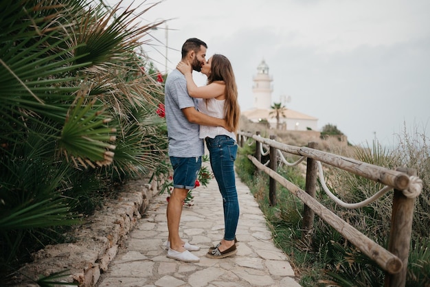 Um homem e sua namorada estão se beijando no caminho de um farol na Espanha