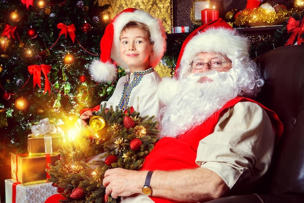 um homem e uma criança estão sentados na frente de uma árvore de Natal