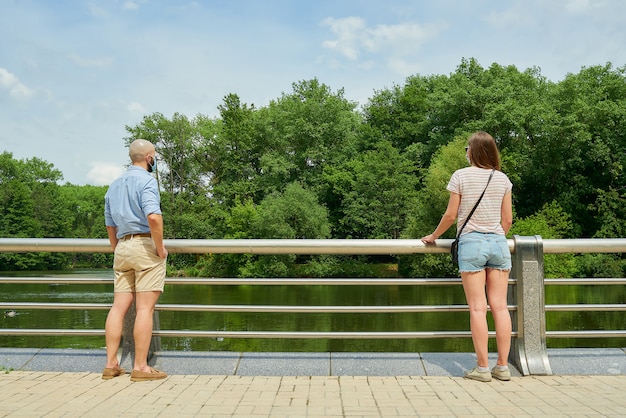 Um homem e uma mulher apreciando a vista do rio mantendo distância alguns metros para evitar a propagação do coronavírus.