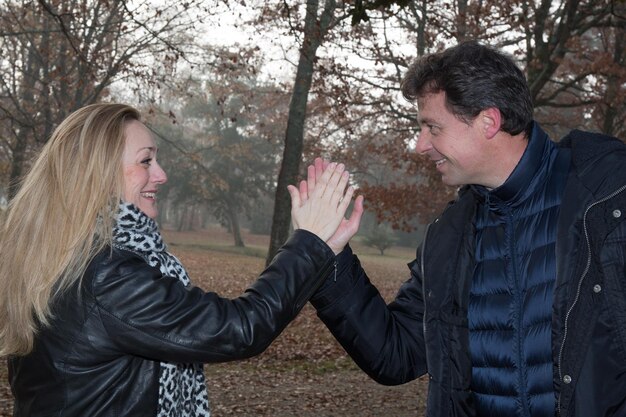 Um homem e uma mulher batem palmas na mão na floresta