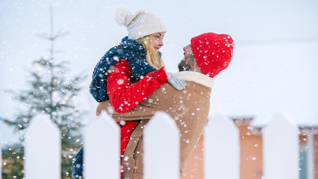 Um homem e uma mulher com roupas de inverno estão abraçados na neve.