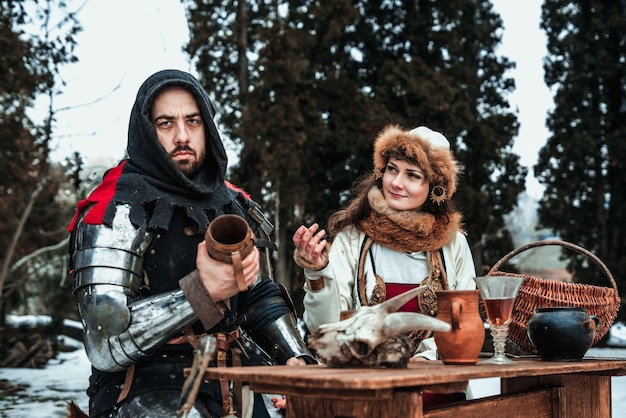 Um homem e uma mulher em trajes históricos estão sentados à mesa