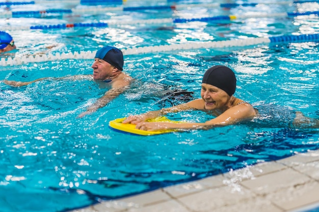 Um homem e uma mulher em uma piscina com uma placa amarela.