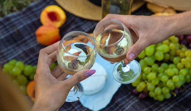 Um homem e uma mulher estão bebendo vinho em um piquenique. Foco seletivo. Natureza.