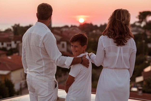 Um homem e uma mulher estão de pé numa varanda e o sol está a pôr-se atrás deles.