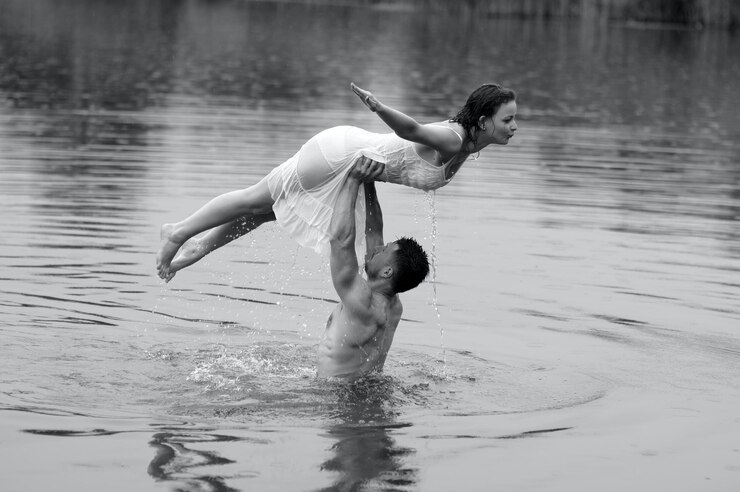 Foto um homem e uma mulher estão na água, eles estão segurando a mulher.