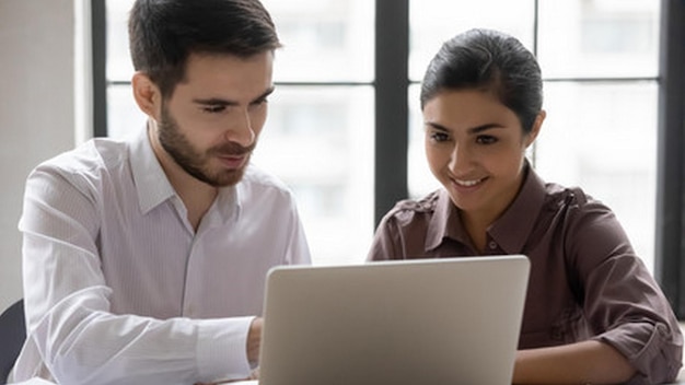 um homem e uma mulher estão olhando para uma tela de laptop