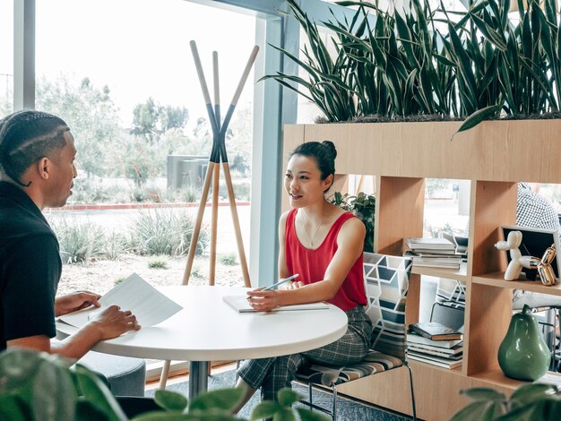 um homem e uma mulher estão sentados em uma mesa com uma planta no fundo