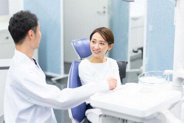 Um homem e uma mulher estão sentados numa cadeira dentária e a sorrir.