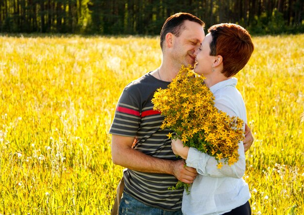 Um homem e uma mulher se beijando, campo de flores amarelas, conceito de amor, conceito de família