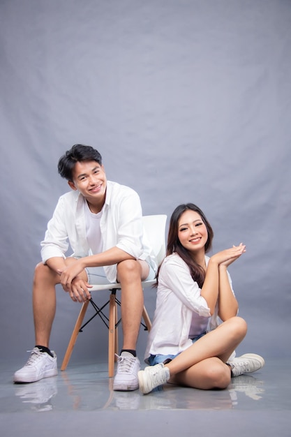 Um homem e uma mulher sentam-se em uma cadeira, um deles está vestindo uma camisa branca casual pré-vestida de moda promocional