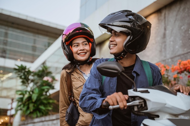 um homem e uma mulher usando capacetes sorrindo enquanto andavam de moto