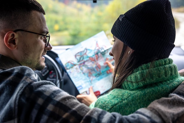 Um homem e uma senhora segurando e olhando para o mapa de papel sentado dentro do carro