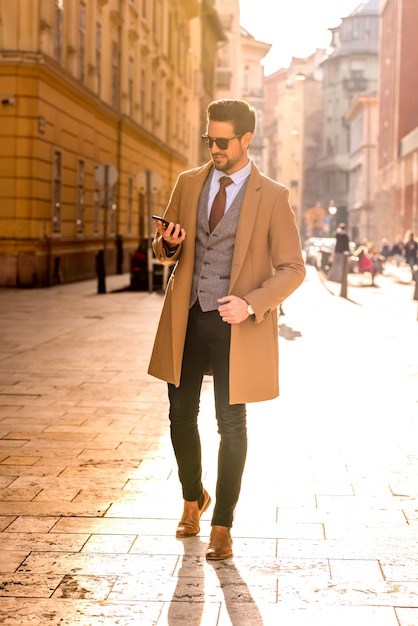 Um homem elegante e bonito usando seu smartphone