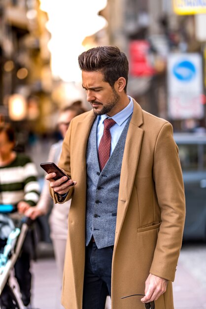 Um homem elegante e bonito usando seu smartphone