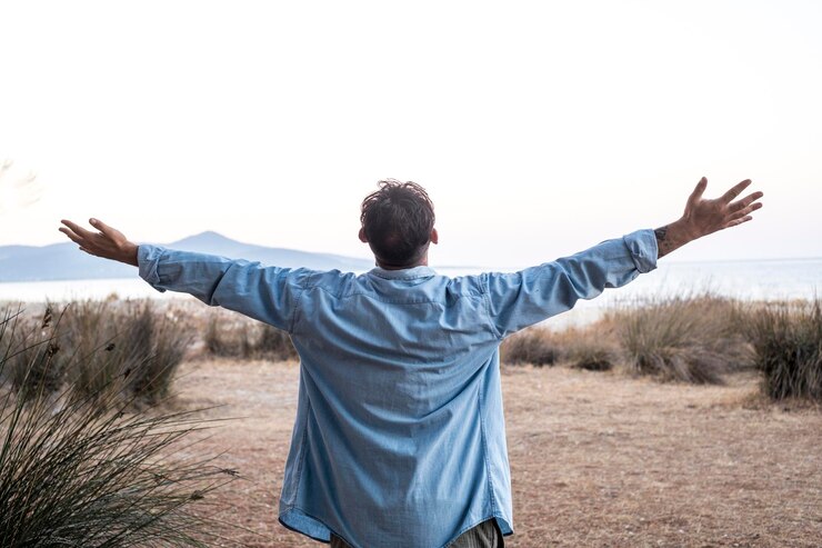 Foto um homem em pé ao ar livre, estendendo os braços em frente à natureza, vista paisagem e céu claro conceito de liberdade e viagens, estilo de vida saudável, condição mental equilibrada turista desfrutando do destino